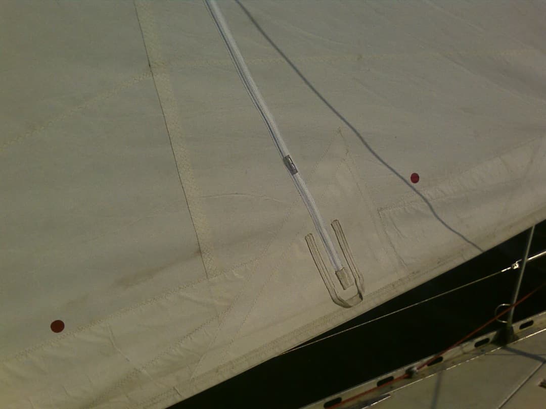 Coutures et repères rouges sur le tissu blanc de la voile.